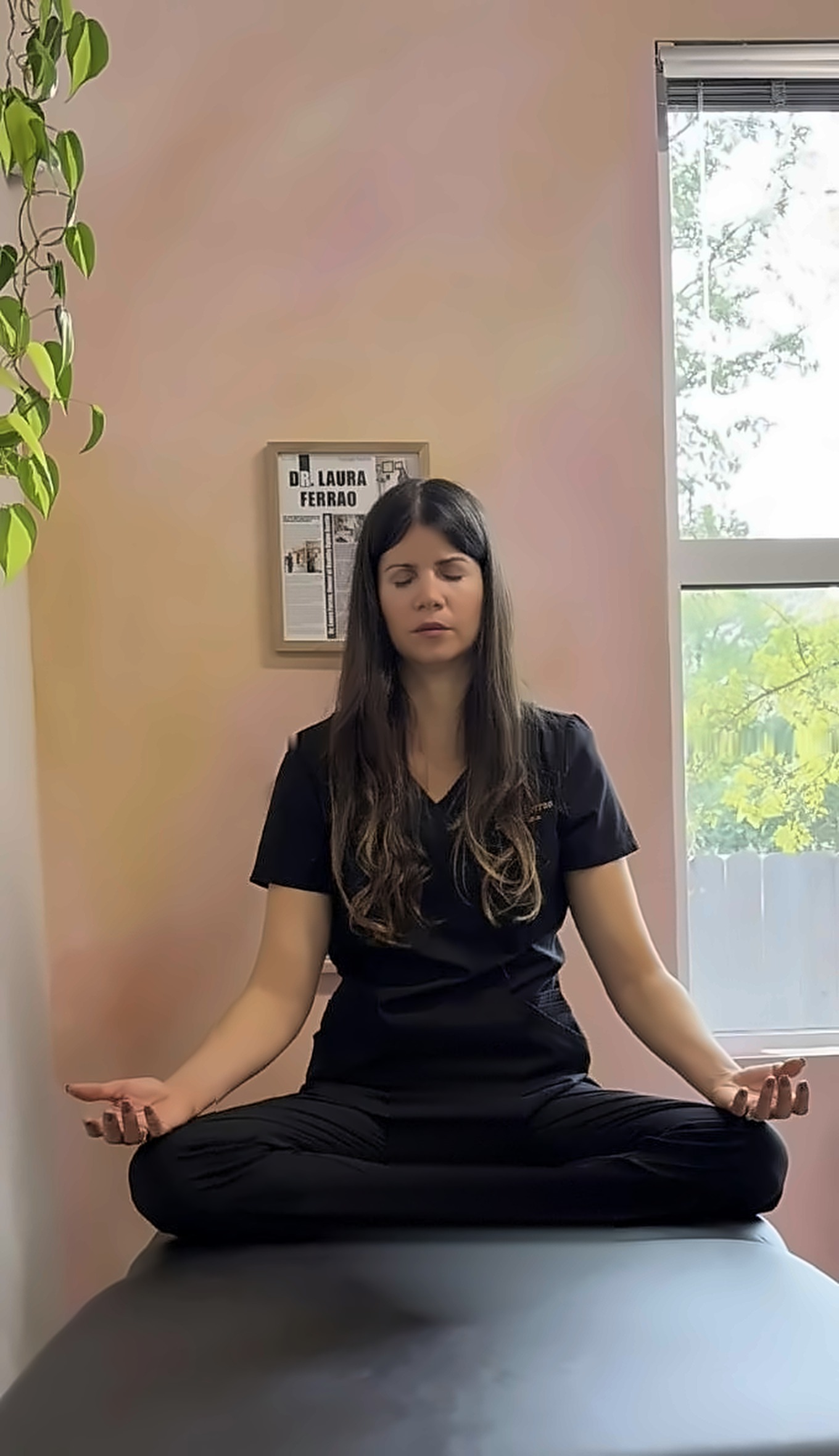 Dr. Laura seated in meditation with her eyes closed by a sunny window