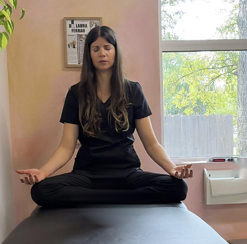 Dr. Laura seated in meditation with her eyes closed by a sunny window