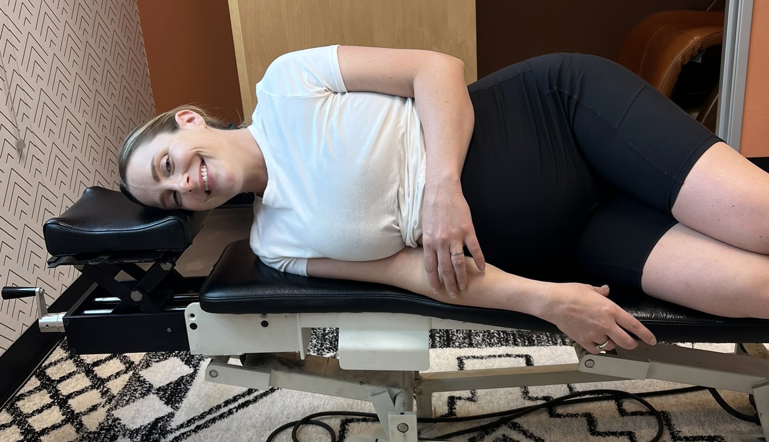 A smiling pregnant mom resting comfortably on her side on the adjusting table