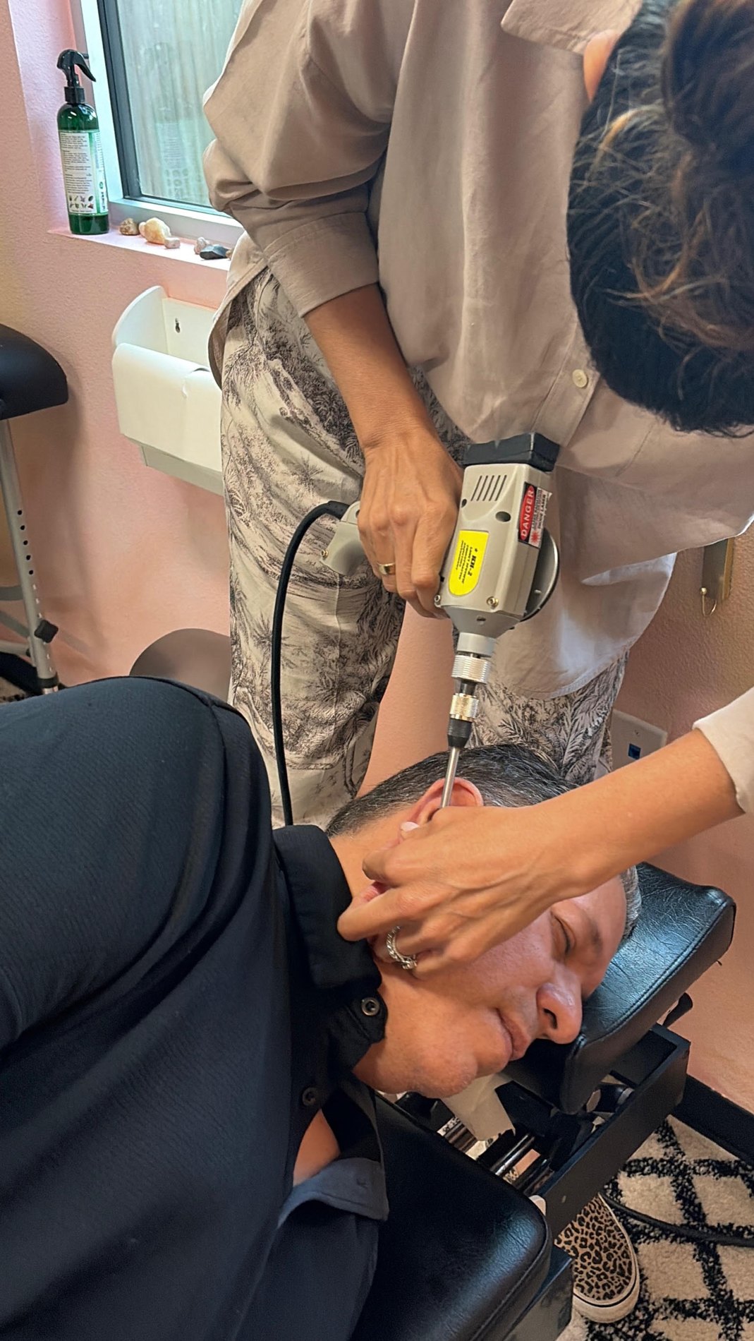 Dr. Laura making a gentle Atlas adjustment with her instrument while the patient rests on his side