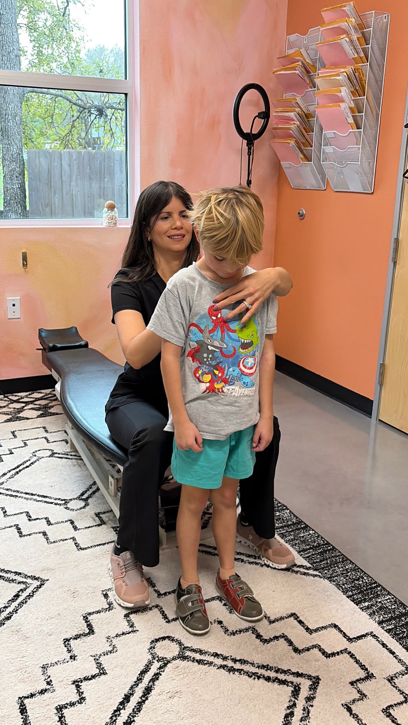 Dr. Laura gently checking the posture of a smiling young boy
