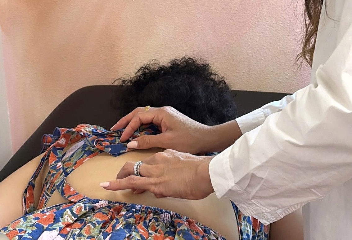 Dr. Laura's hands gently checking the alignment of a patient's upper back